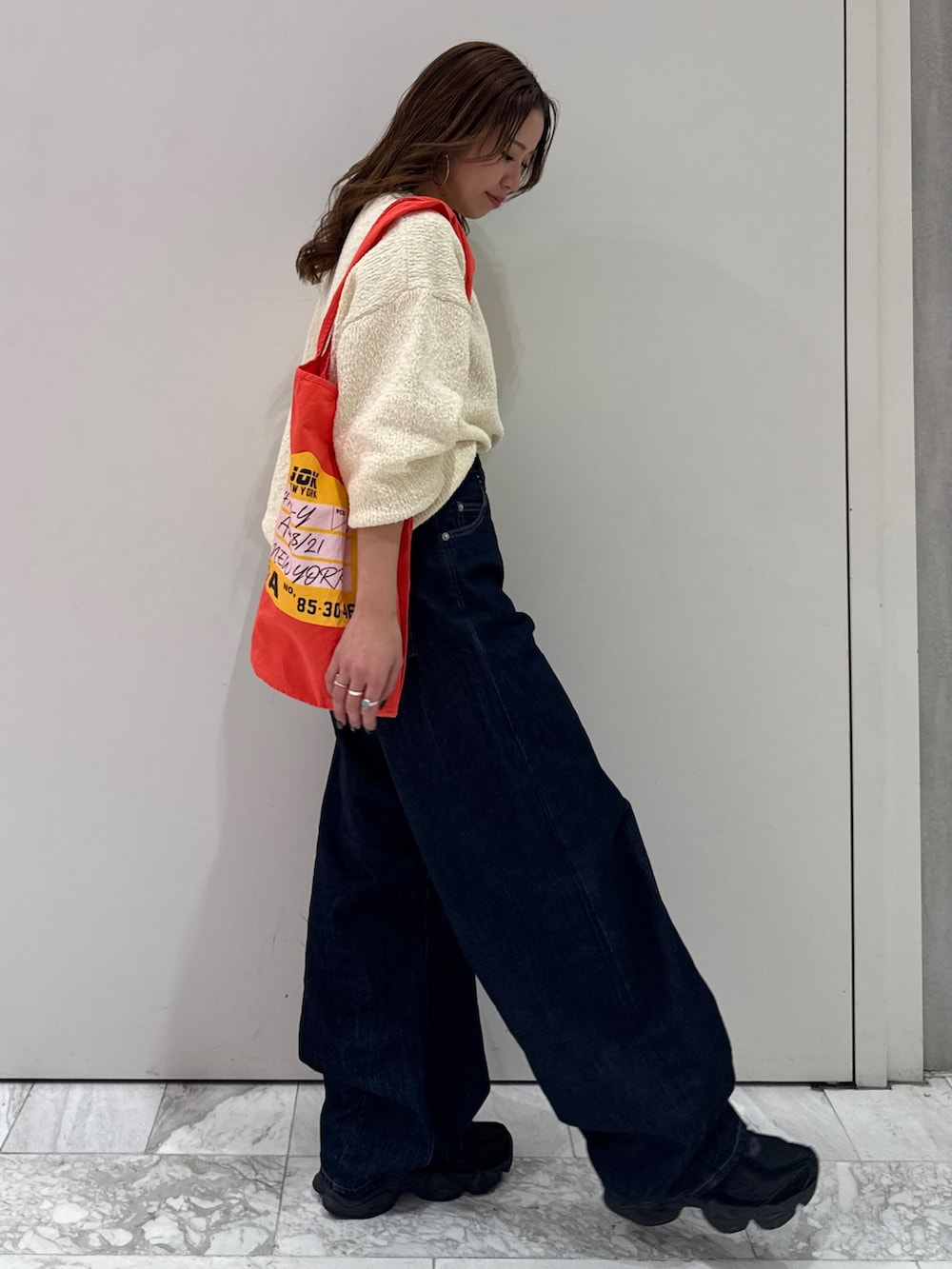 ブルー系のデニムパンツ、ホワイト系のニット/セーター、オレンジ系のトートバッグを着用したレディースの冬コーディネートの4枚目の写真