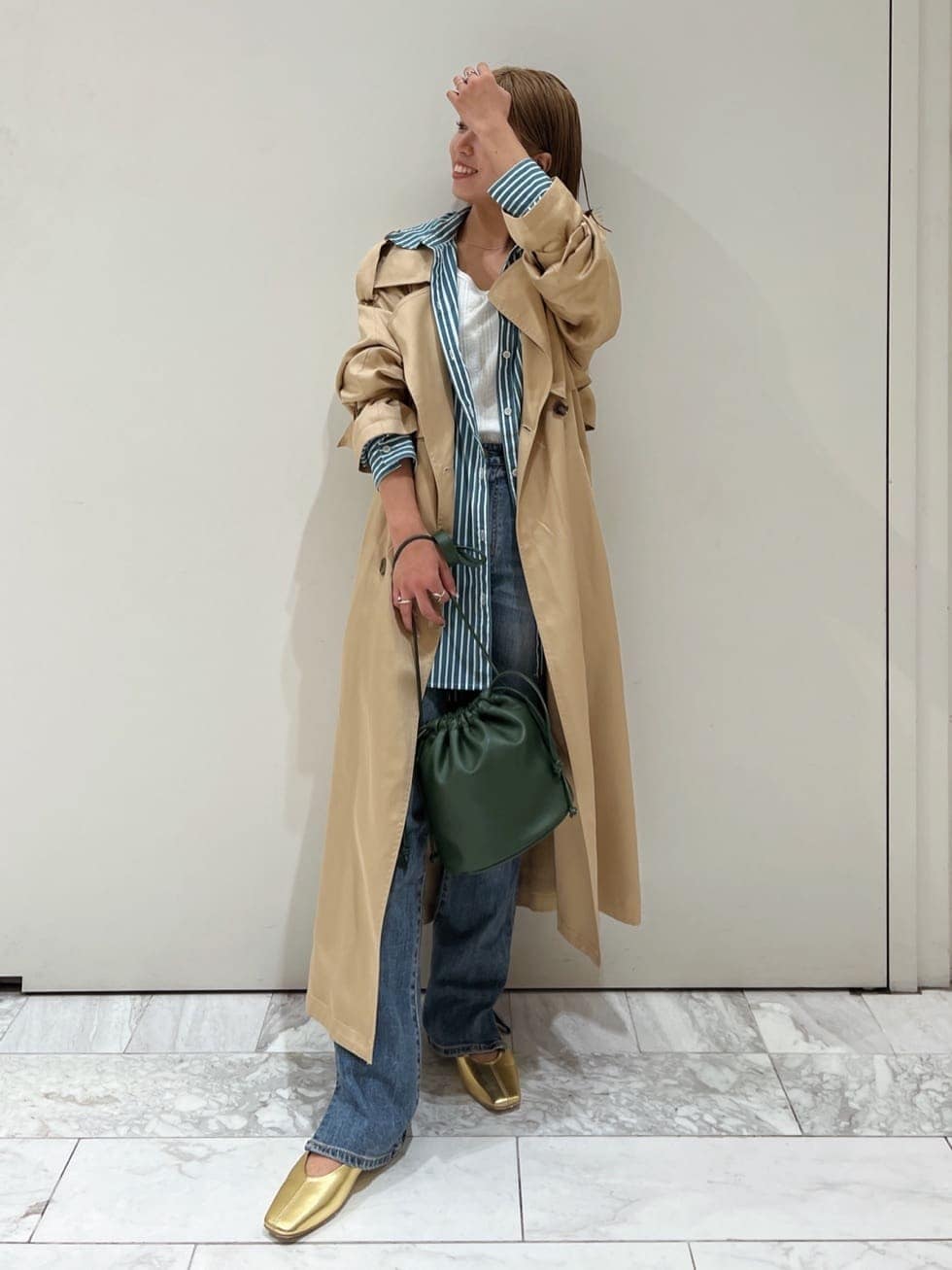 ベージュ系のトレンチコート、グリーン系のシャツ/ブラウス、ブルー系のデニムパンツを着用したレディースの夏コーディネートの2枚目の写真