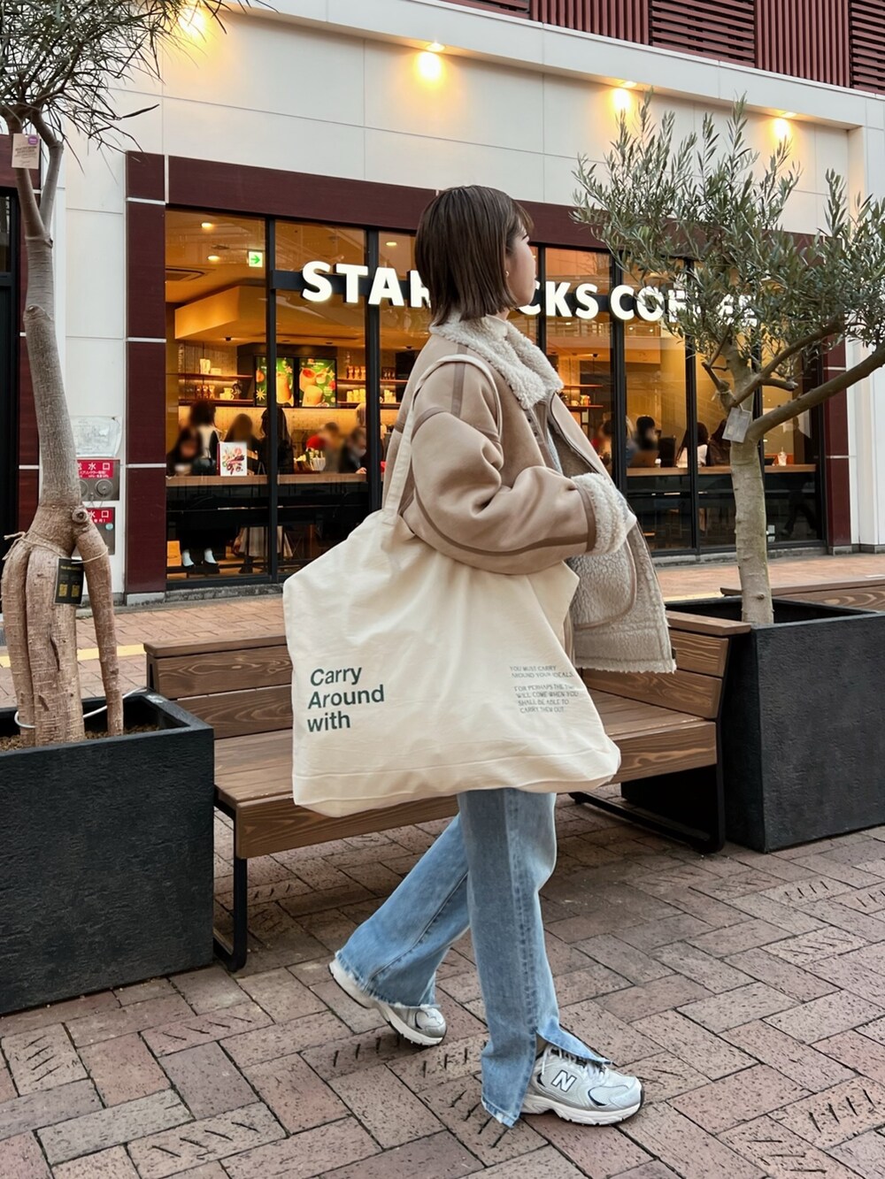 ベージュ系のムートンコート、ホワイト系のハンドバッグ、グレー系のニット/セーターを着用したレディースの冬コーディネートの5枚目の写真