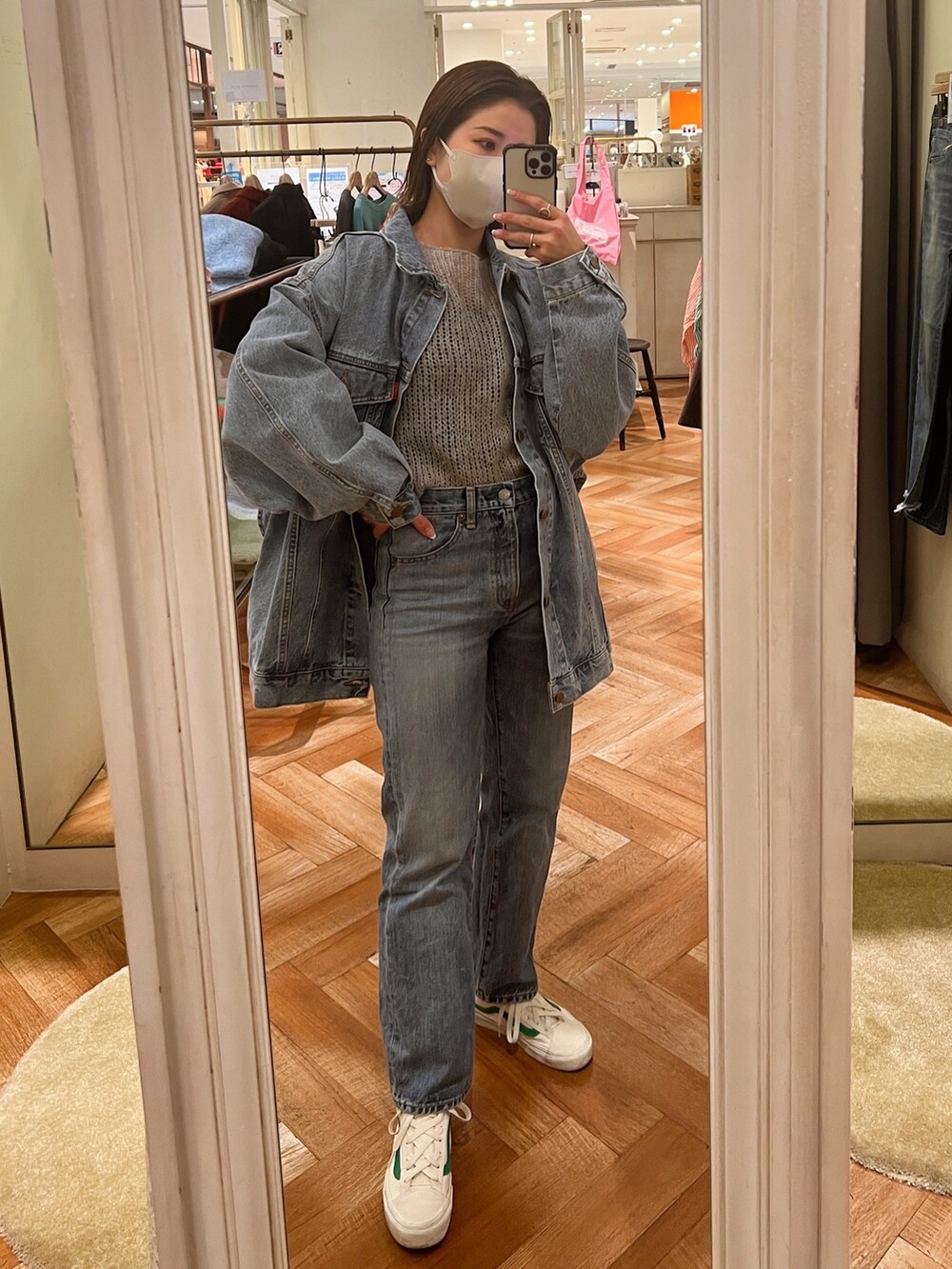 ホワイト系のデニムジャケット、グレー系のニット/セーター、ブルー系のデニムパンツを着用したレディースの冬コーディネートの2枚目の写真