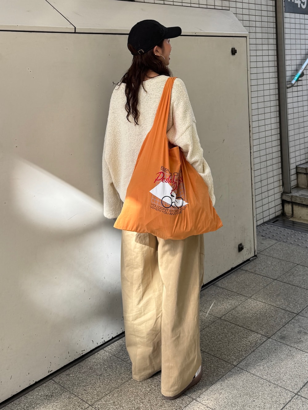 ベージュ系のチノパンツ、ホワイト系のニット/セーター、オレンジ系のエコバッグ/サブバッグを着用したレディースの冬コーディネートの3枚目の写真