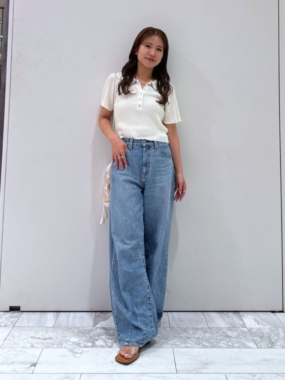 その他のサンダル、ホワイト系のハンドバッグ、ブルー系のデニムパンツを着用したレディースの夏コーディネートの2枚目の写真