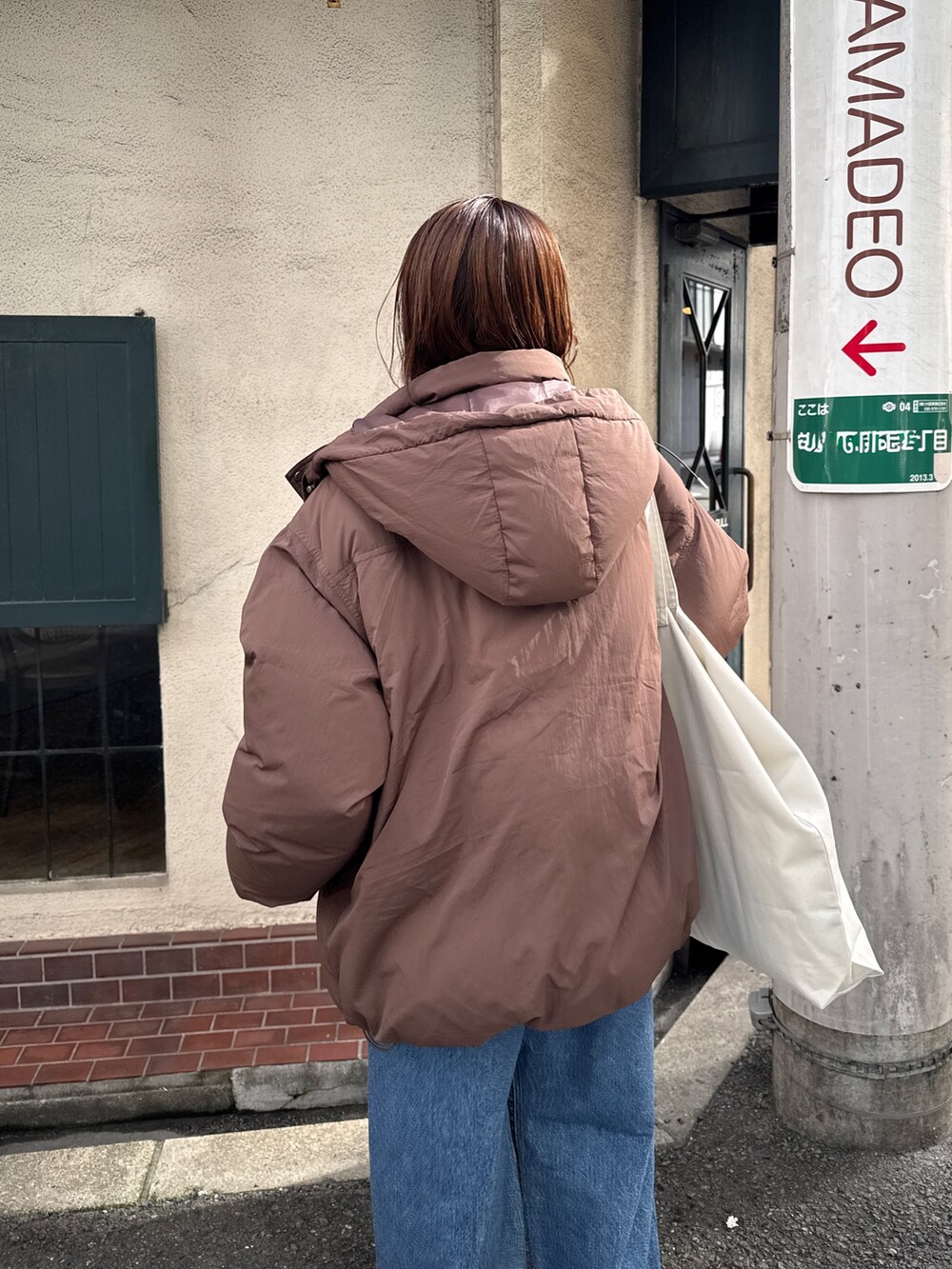 ブラウン系のダウンジャケット/コート、ホワイト系のニット/セーター、ブルー系のデニムパンツを着用したレディースの秋コーディネートの5枚目の写真