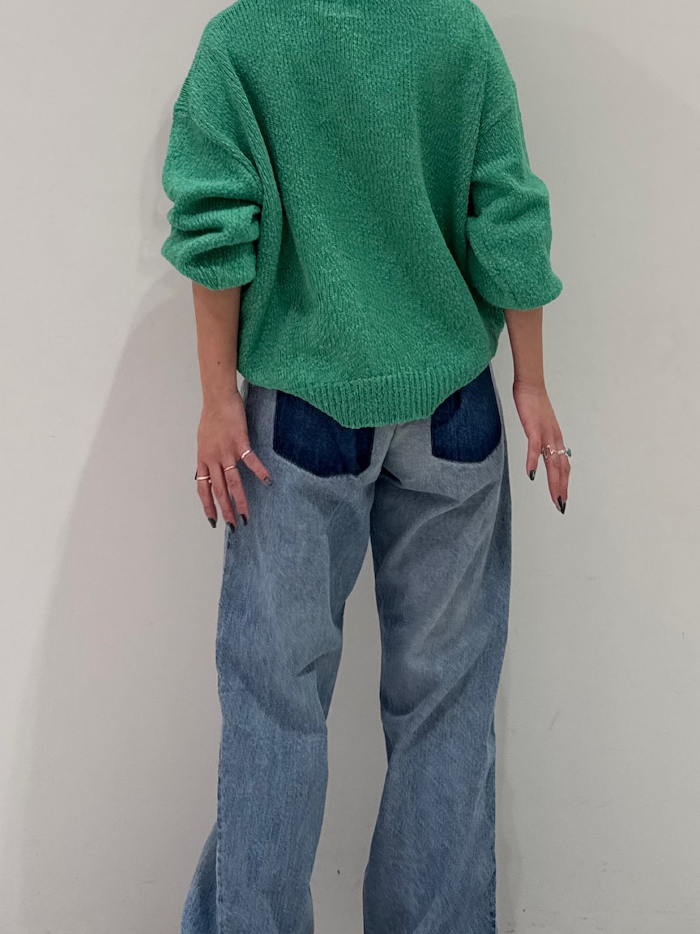 ブルー系のデニムパンツ、グリーン系のニット/セーター、シルバー系のネックレスを着用したレディースの冬コーディネートの3枚目の写真