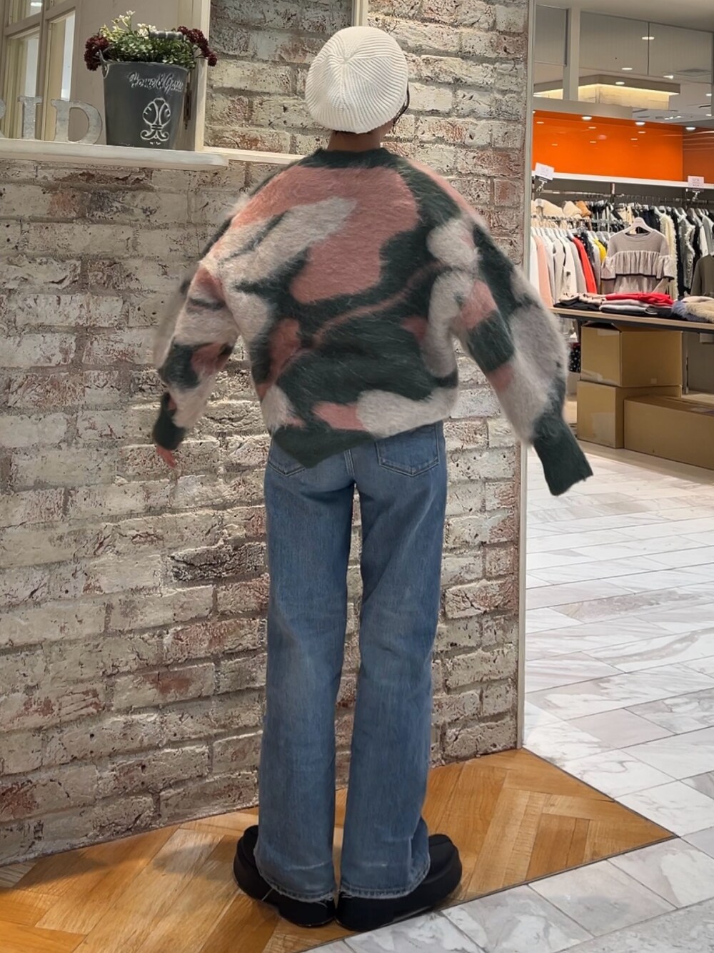 ブラック系のブーツ、グリーン系のニット/セーター、ブルー系のデニムパンツを着用したレディースの秋コーディネートの5枚目の写真