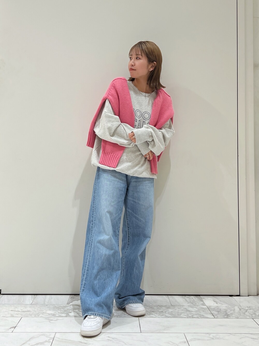 ピンク系のニット/セーター、グレー系のスウェット、ブルー系のデニムパンツを着用したレディースの秋コーディネートの2枚目の写真