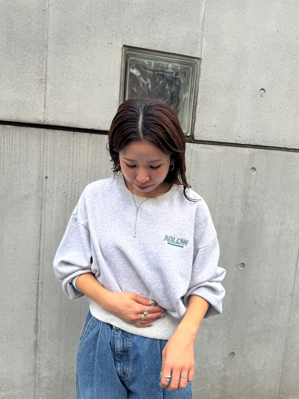 ブルー系のデニムパンツ、グレー系のスウェット、ブラウン系のスニーカーを着用したレディースの秋コーディネートの6枚目の写真