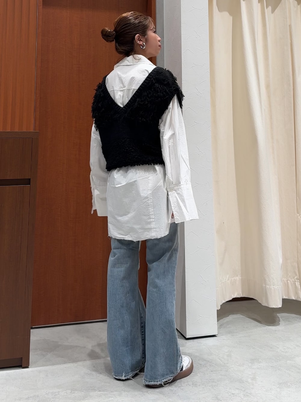 ブラック系のベスト、ホワイト系のシャツ/ブラウス、ブルー系のデニムパンツを着用したレディースの春コーディネートの5枚目の写真