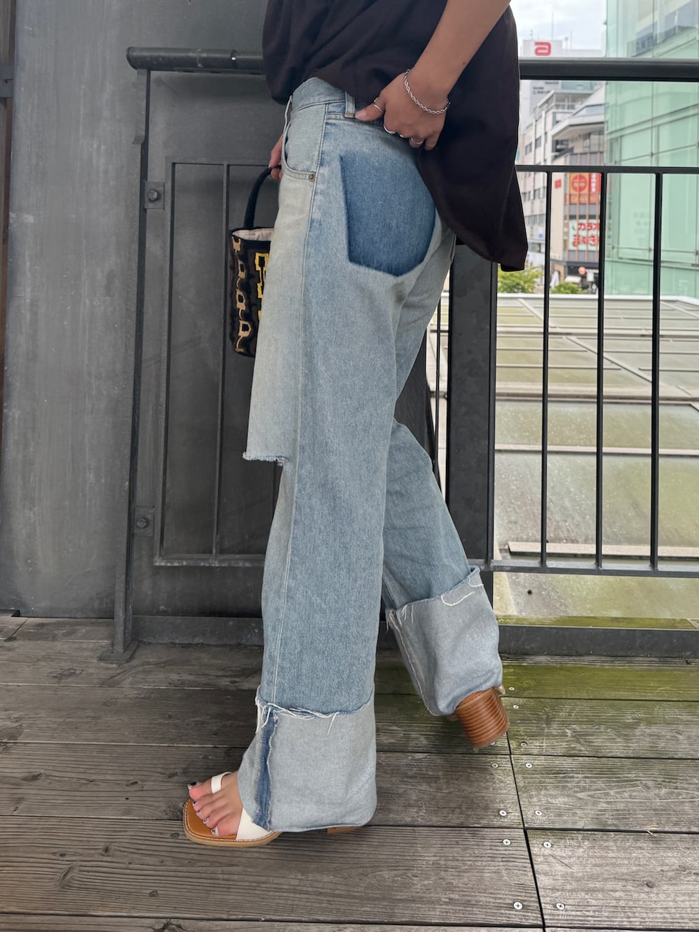 ブルー系のデニムパンツ、ホワイト系のサンダル、ブラウン系のハンドバッグを着用したレディースの夏コーディネートの9枚目の写真