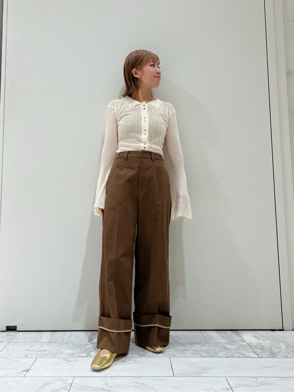 ブラウン系のチノパンツ、ゴールド系のパンプス、ホワイト系のカーディガン/ボレロを着用したレディースの夏コーディネートの3枚目の写真