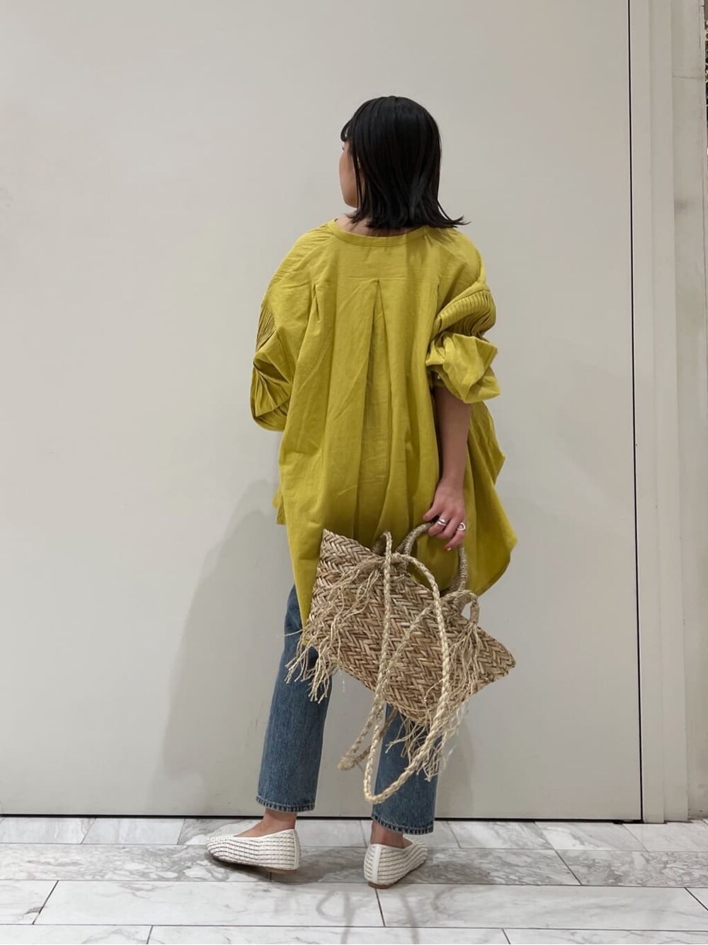 ホワイト系のパンプス、イエロー系のシャツ/ブラウス、ベージュ系のかごバッグを着用したレディースの春コーディネートの5枚目の写真