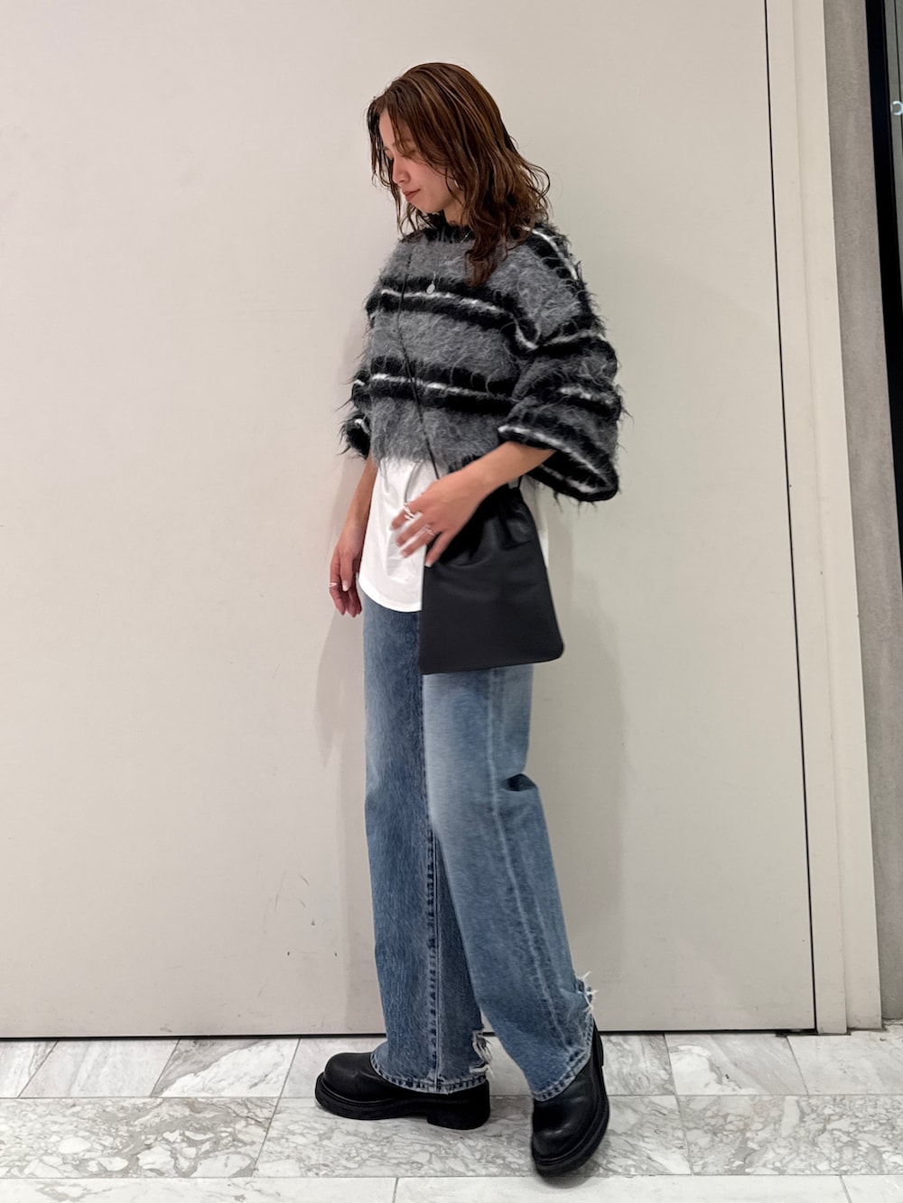 ブラック系のニット/セーター、ホワイト系のTシャツ/カットソー、ブルー系のデニムパンツを着用したレディースの冬コーディネートの6枚目の写真