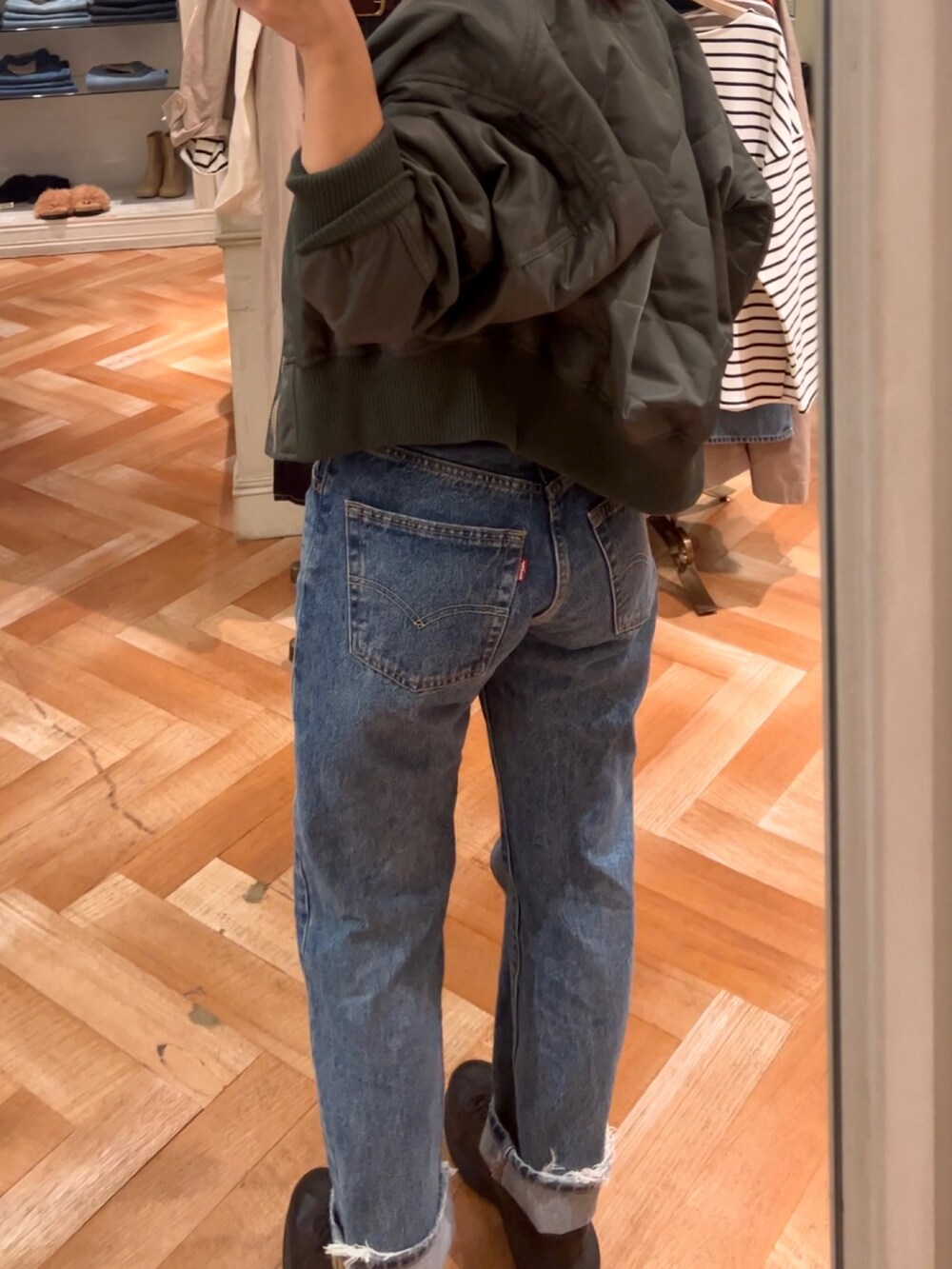 ブラック系のキャミソール、ブルー系のデニムパンツ、グリーン系のブルゾンを着用したレディースの秋コーディネートの4枚目の写真