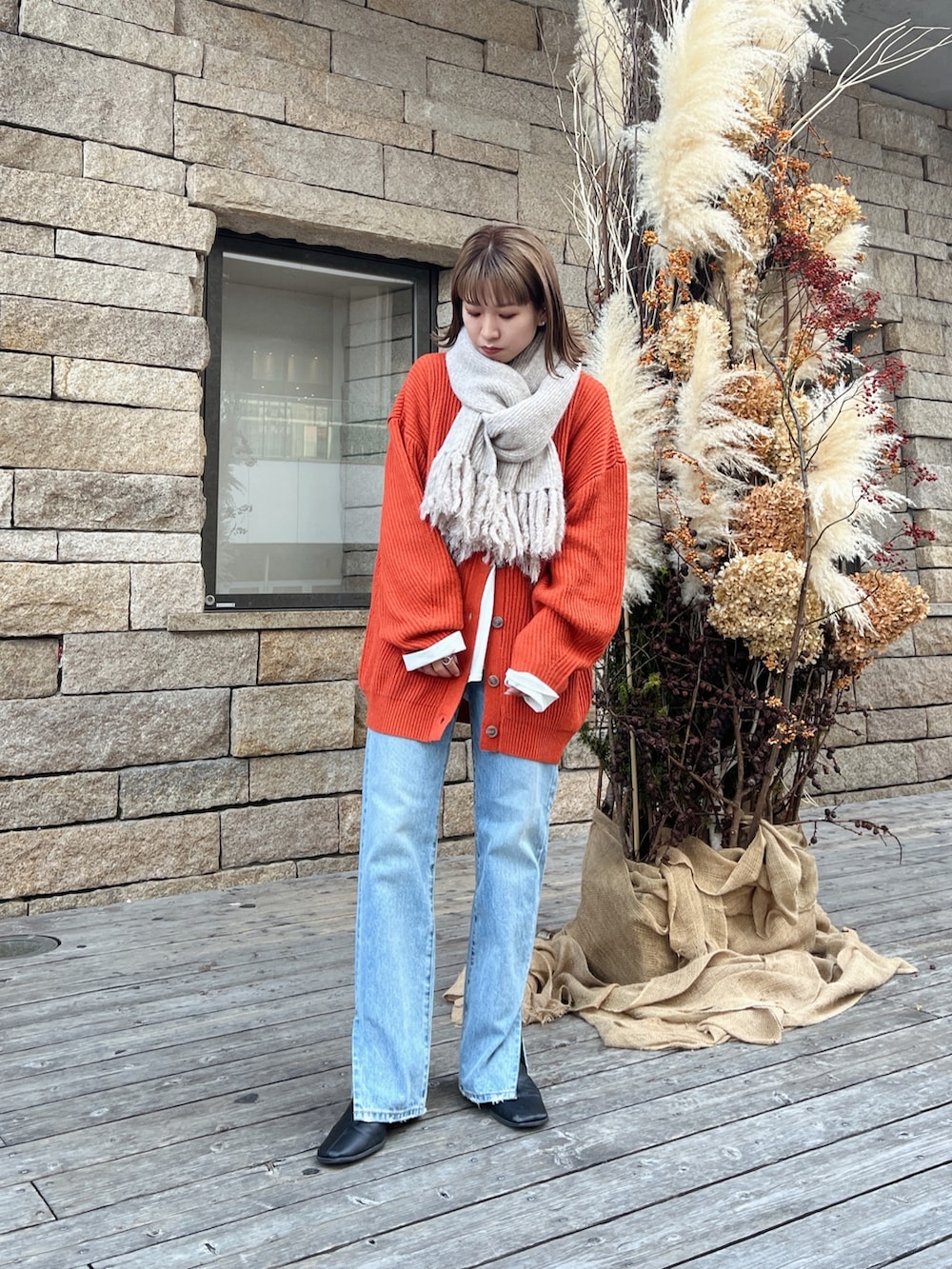 オレンジ系のカーディガン/ボレロ、ブルー系のデニムパンツを着用したレディースの秋コーディネートの4枚目の写真