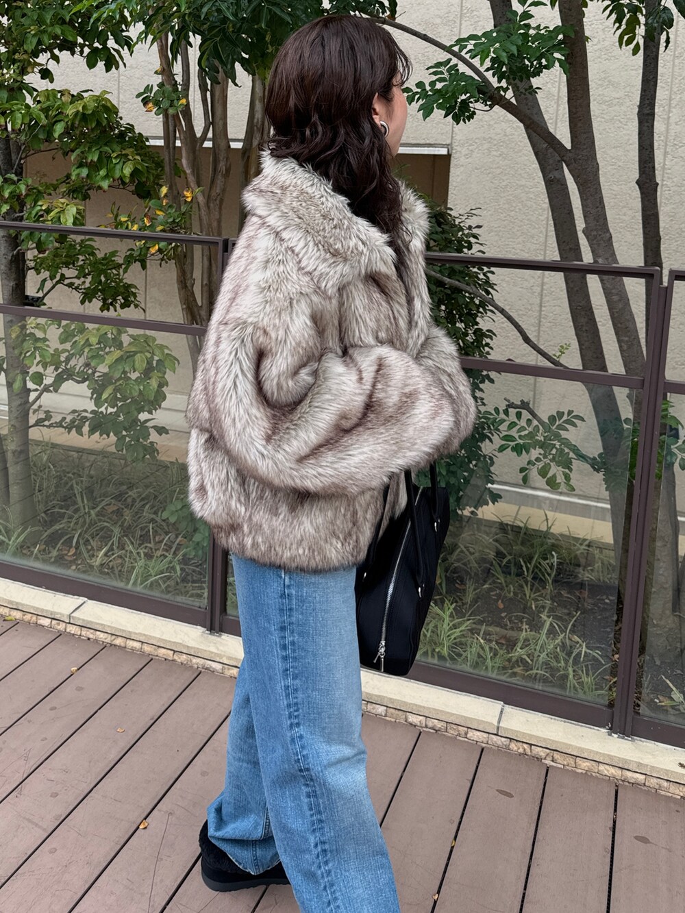 ベージュ系のその他アウター、ブルー系のデニムパンツ、ブラック系のハンドバッグを着用したレディースの秋コーディネートの6枚目の写真