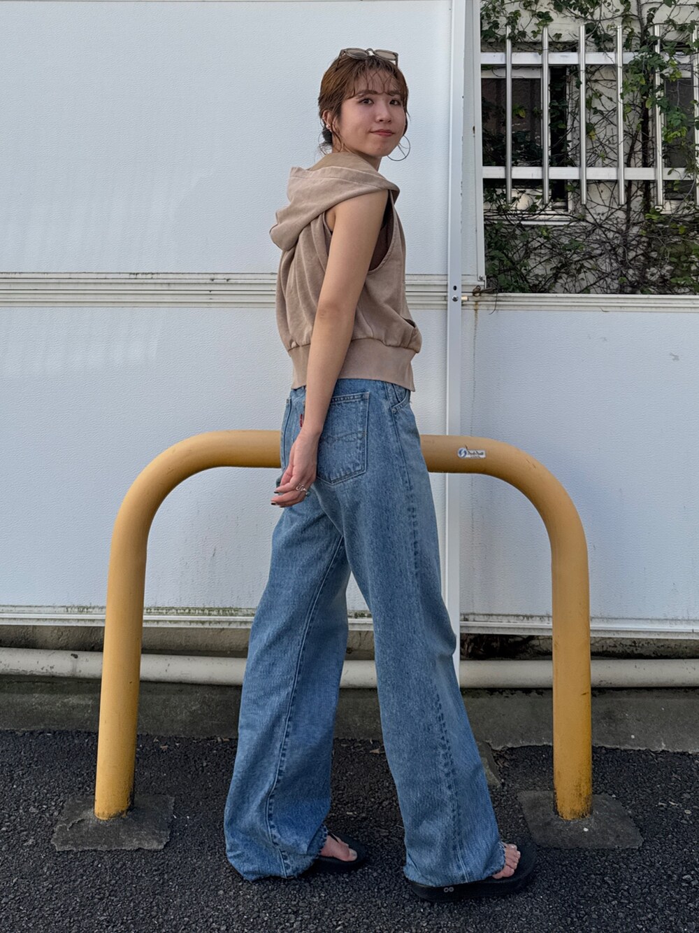 ベージュ系のパーカー、ブルー系のデニムパンツを着用したレディースの夏コーディネートの3枚目の写真