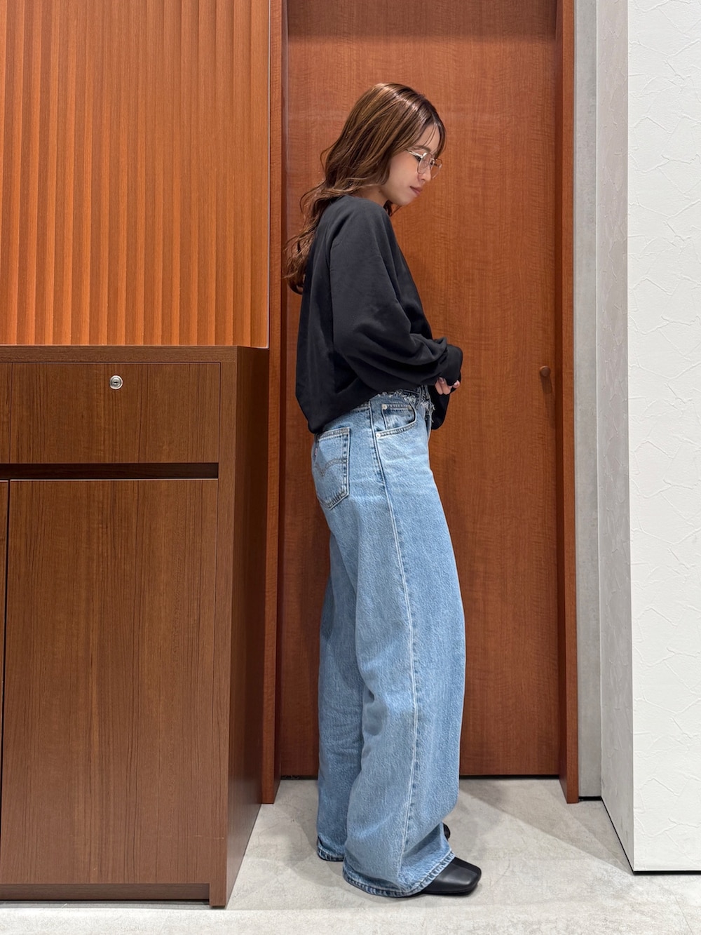 ブルー系のデニムパンツ、ブラック系のスウェット、シルバー系のメガネを着用したレディースの秋コーディネートの2枚目の写真
