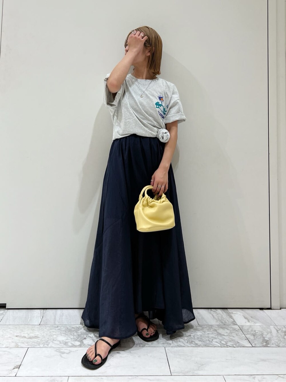ブラック系のサンダル、ブルー系のスカート、イエロー系のハンドバッグを着用したレディースの春コーディネートの3枚目の写真