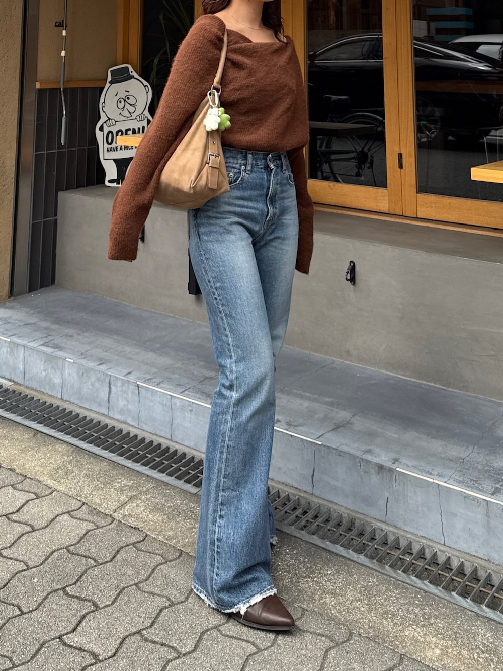 ブルー系のデニムパンツ、ブラウン系のブーツ、ブラウン系のニット/セーターを着用したレディースの秋コーディネートの2枚目の写真