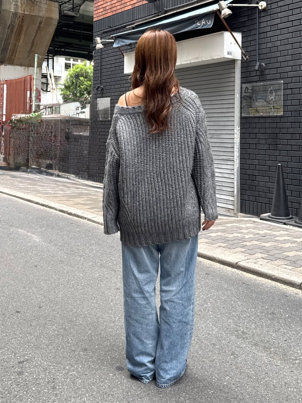 グレー系のニット/セーター、ブルー系のデニムパンツ、ブラック系のサンダルを着用したレディースの秋コーディネートの3枚目の写真