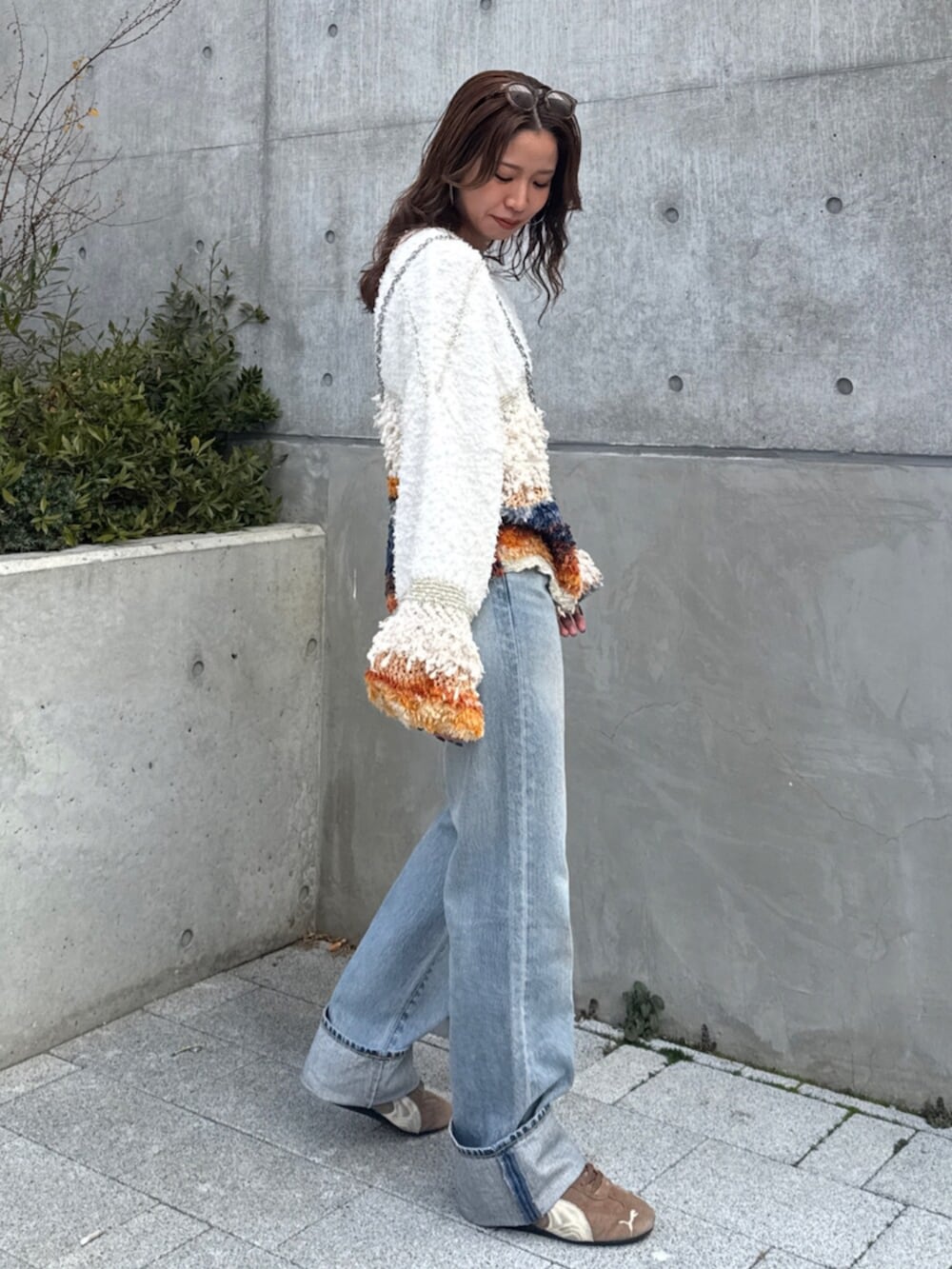 ブルー系のデニムパンツ、ホワイト系のニット/セーター、ブラウン系のスニーカーを着用したレディースの冬コーディネートの6枚目の写真