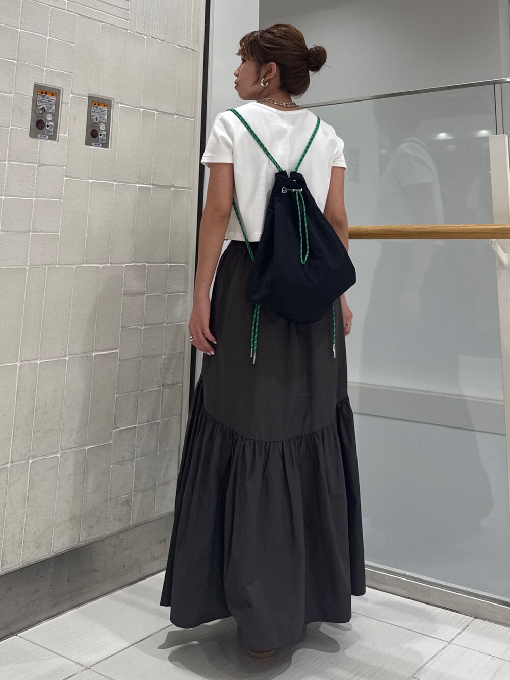 グレー系のスカート、シルバー系のサンダル、ホワイト系のTシャツ/カットソーを着用したレディースの春コーディネートの4枚目の写真