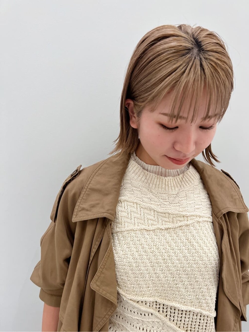 ブラウン系のトレンチコート、ブラック系のブーツ、ホワイト系のニット/セーターを着用したレディースの夏コーディネートの5枚目の写真