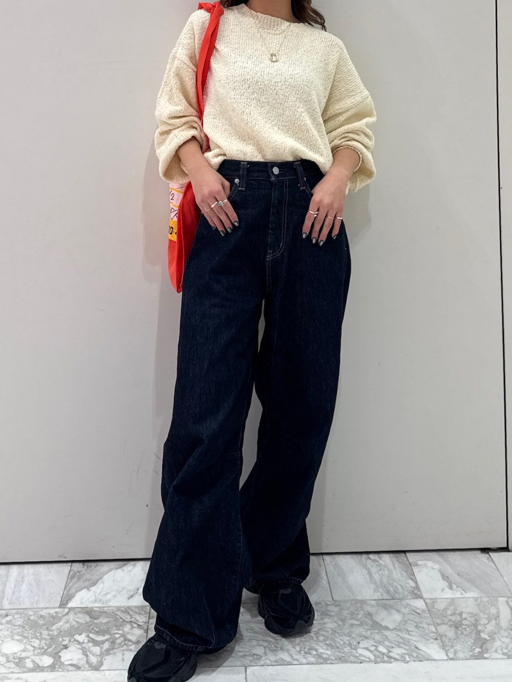 ブルー系のデニムパンツ、ホワイト系のニット/セーター、オレンジ系のトートバッグを着用したレディースの冬コーディネートの2枚目の写真