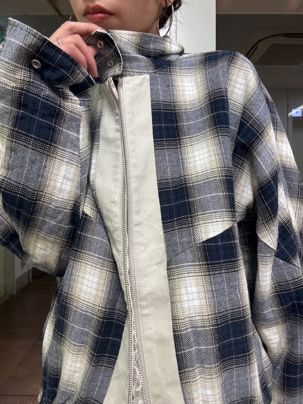 ベージュ系のブルゾン、ホワイト系のワンピース、ブルー系のデニムパンツを着用したレディースの冬コーディネートの6枚目の写真