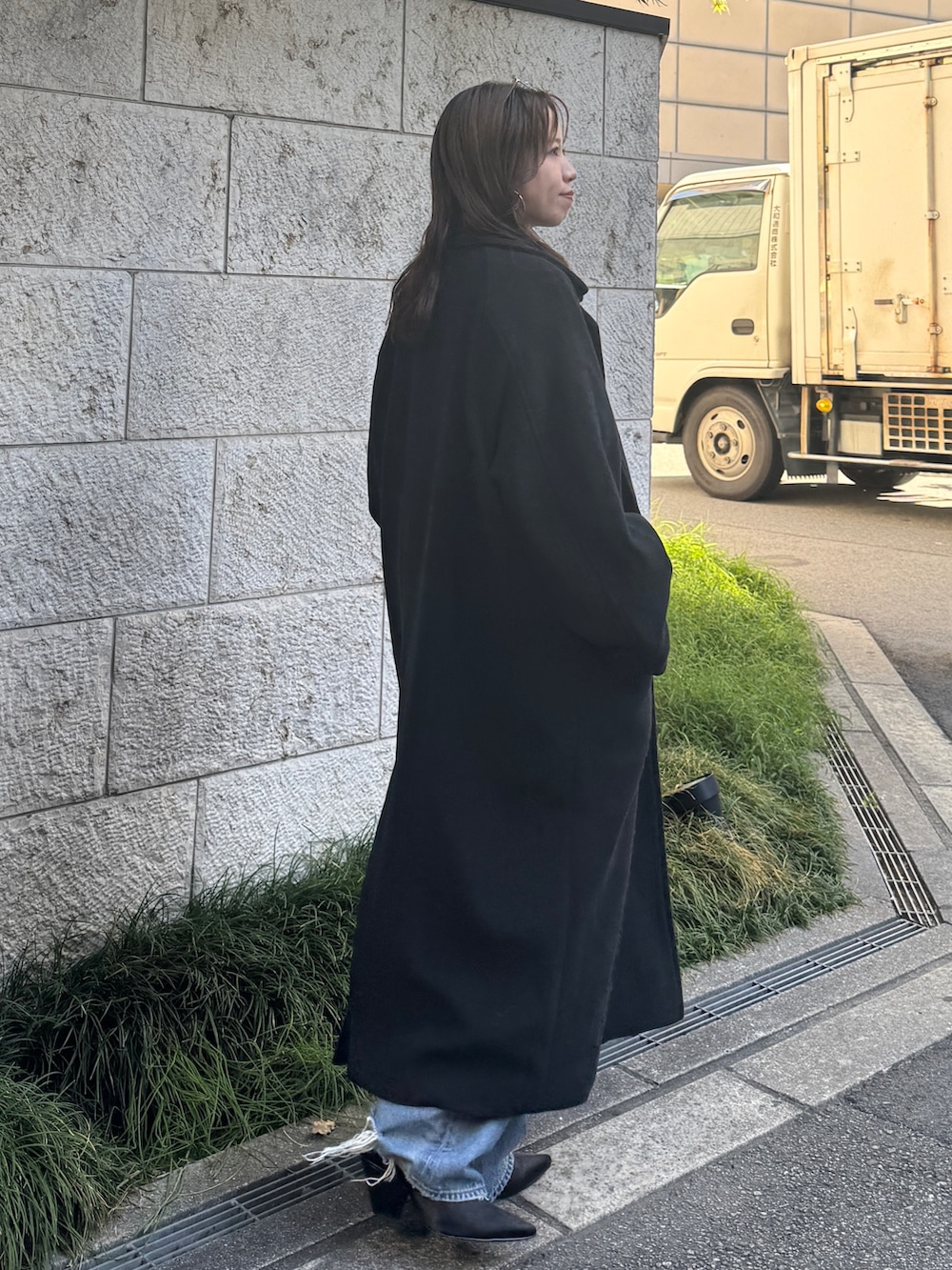 ブルー系のデニムパンツ、ブルー系のニット/セーター、ブラック系のチェスターコートを着用したレディースの秋コーディネートの7枚目の写真