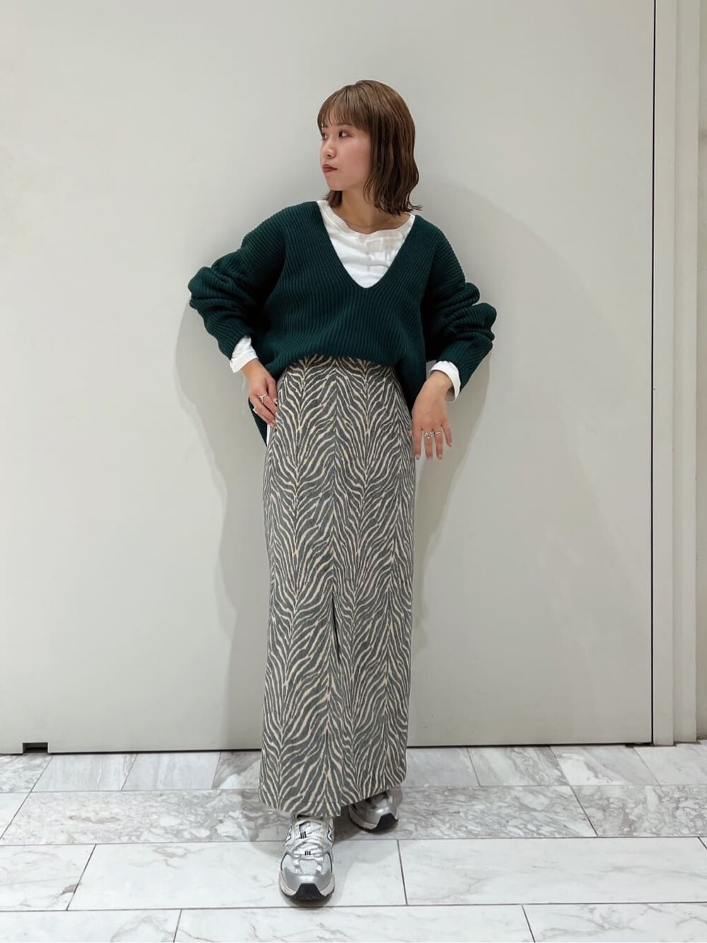 ホワイト系のTシャツ/カットソー、ブルー系のスカート、グリーン系のニット/セーターを着用したレディースの秋コーディネートの4枚目の写真