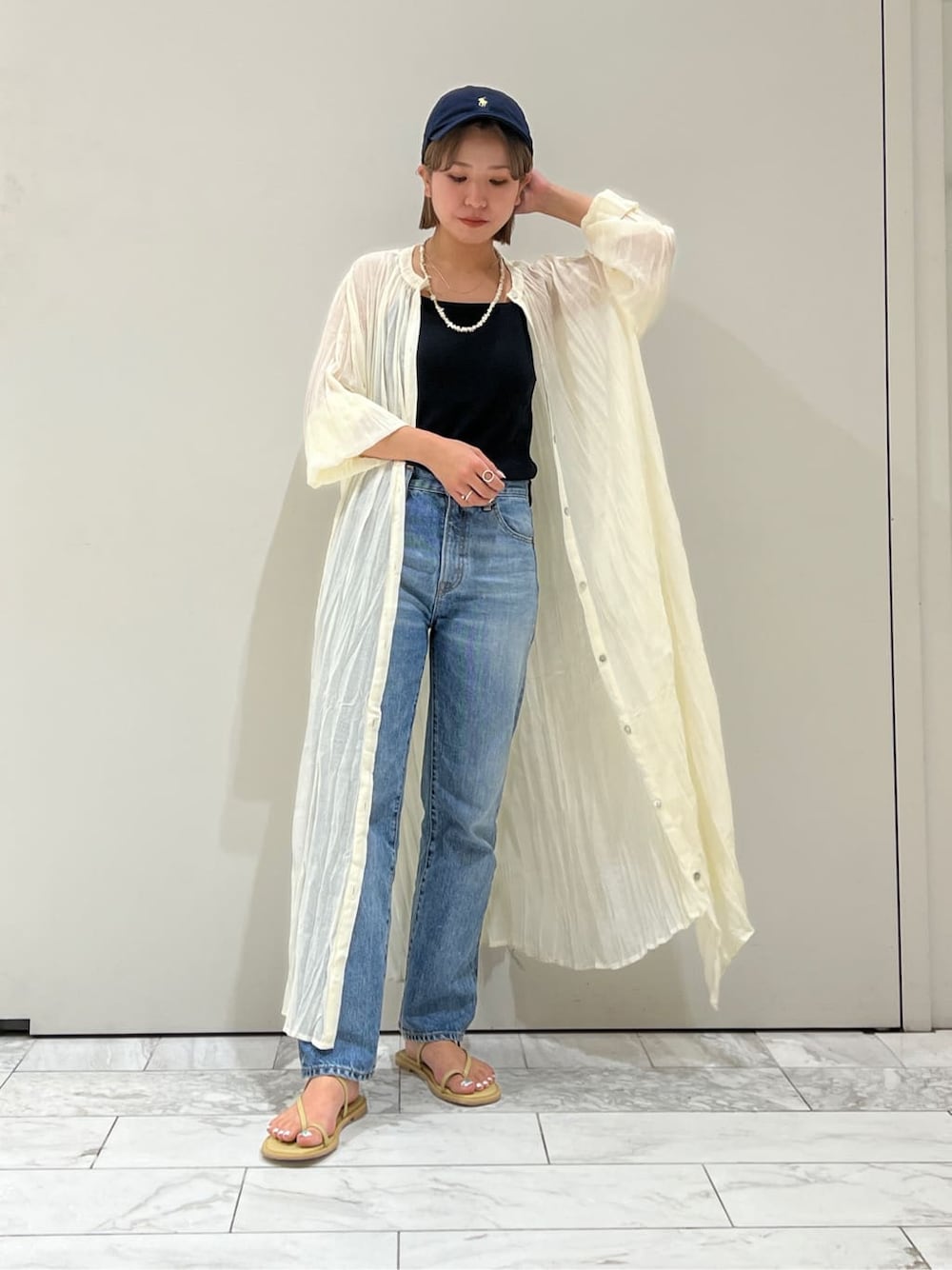 ブルー系のデニムパンツ、グリーン系のサンダル、ブラック系のキャミソールを着用したレディースの夏コーディネートの3枚目の写真