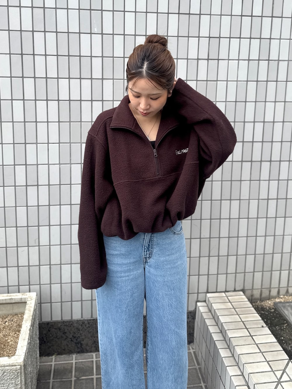 ブラウン系のパーカー、ブルー系のデニムパンツ、ブラック系のサンダルを着用したレディースの秋コーディネートの6枚目の写真
