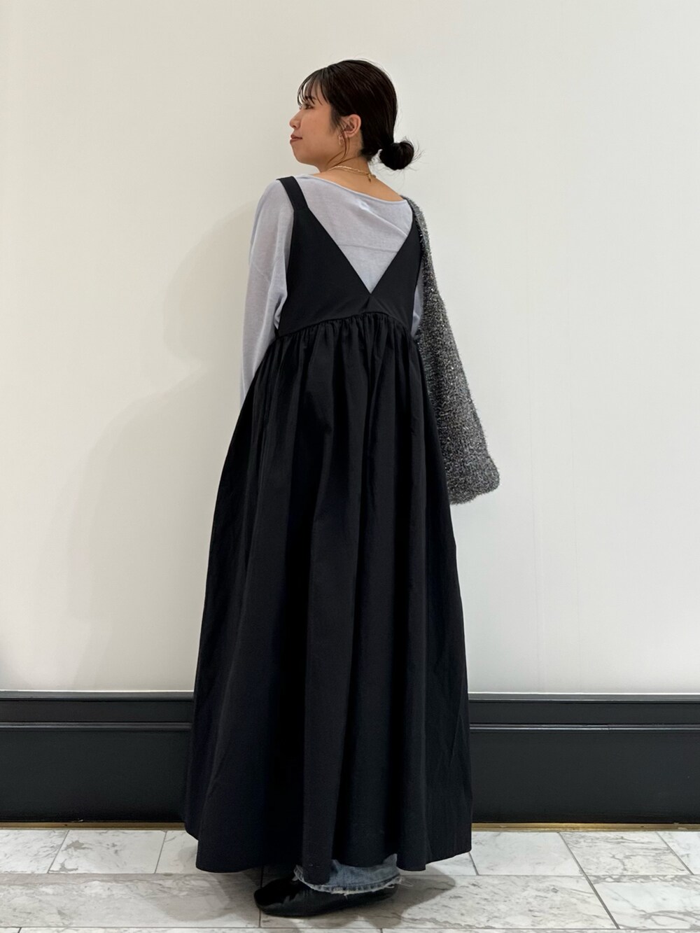 ブラック系のワンピース、ブルー系のニット/セーター、ブルー系のデニムパンツを着用したレディースの春コーディネートの5枚目の写真