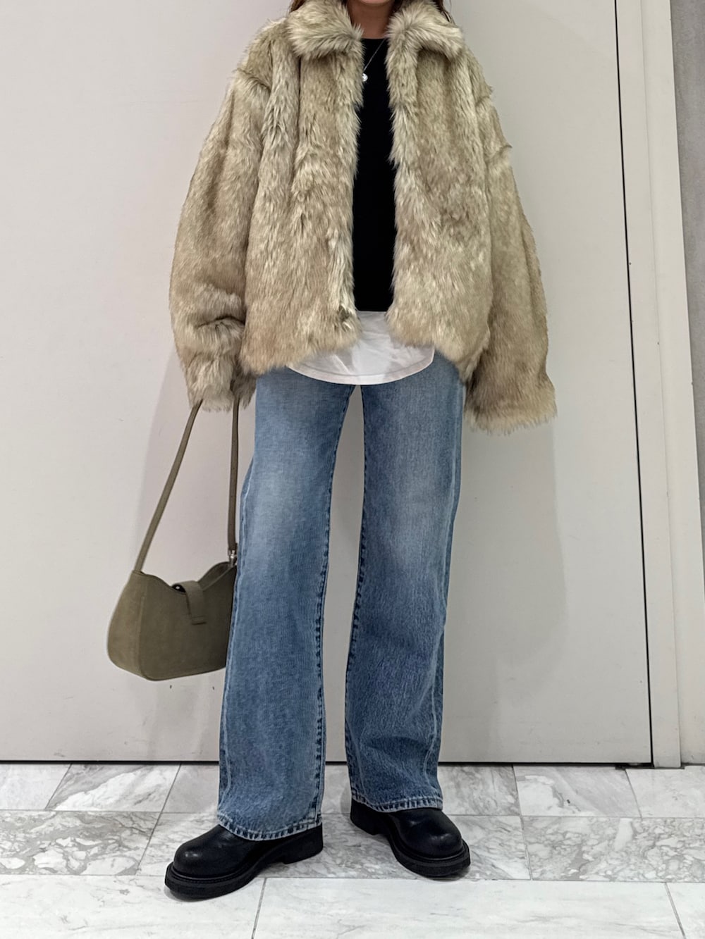 ベージュ系のダウンジャケット/コート、グリーン系のハンドバッグ、ブルー系のデニムパンツを着用したレディースの冬コーディネートの6枚目の写真