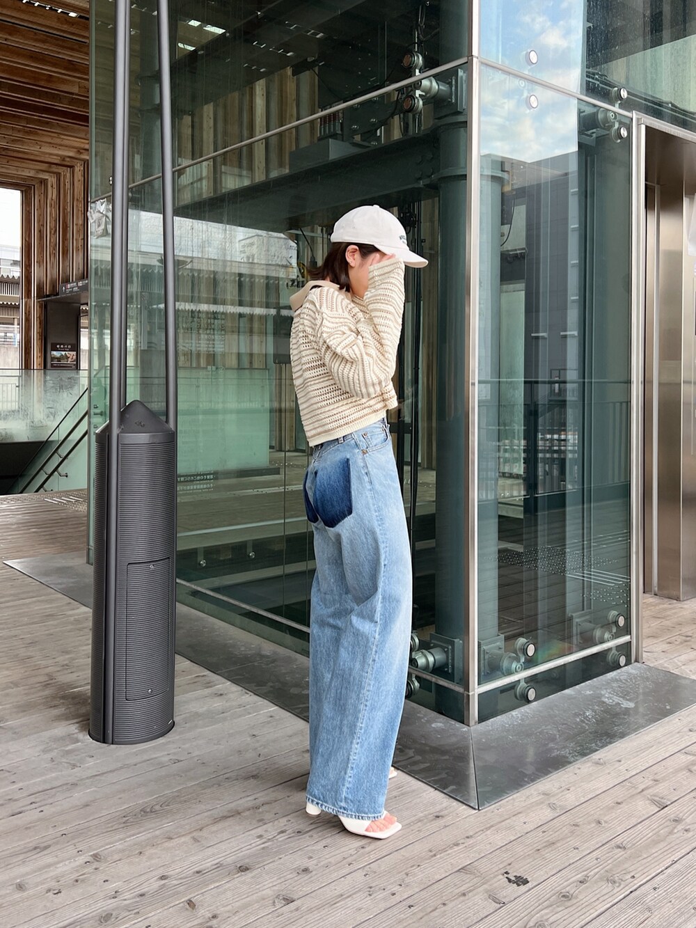 ベージュ系のニット/セーター、ブルー系のデニムパンツ、ホワイト系のサンダルを着用したレディースの春コーディネートの2枚目の写真