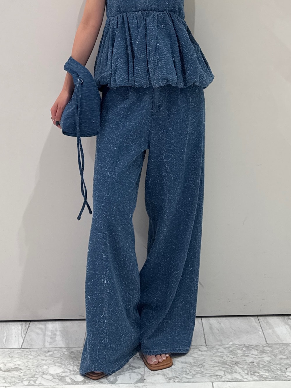 ブルー系のチューブトップ、ブルー系のデニムパンツ、ブルー系のハンドバッグを着用したレディースの春コーディネートの4枚目の写真