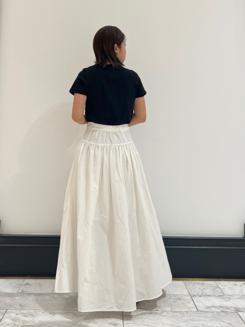 ホワイト系のスカート、ブラック系のTシャツ/カットソー、ブラック系のパンプスを着用したレディースの春コーディネートの3枚目の写真