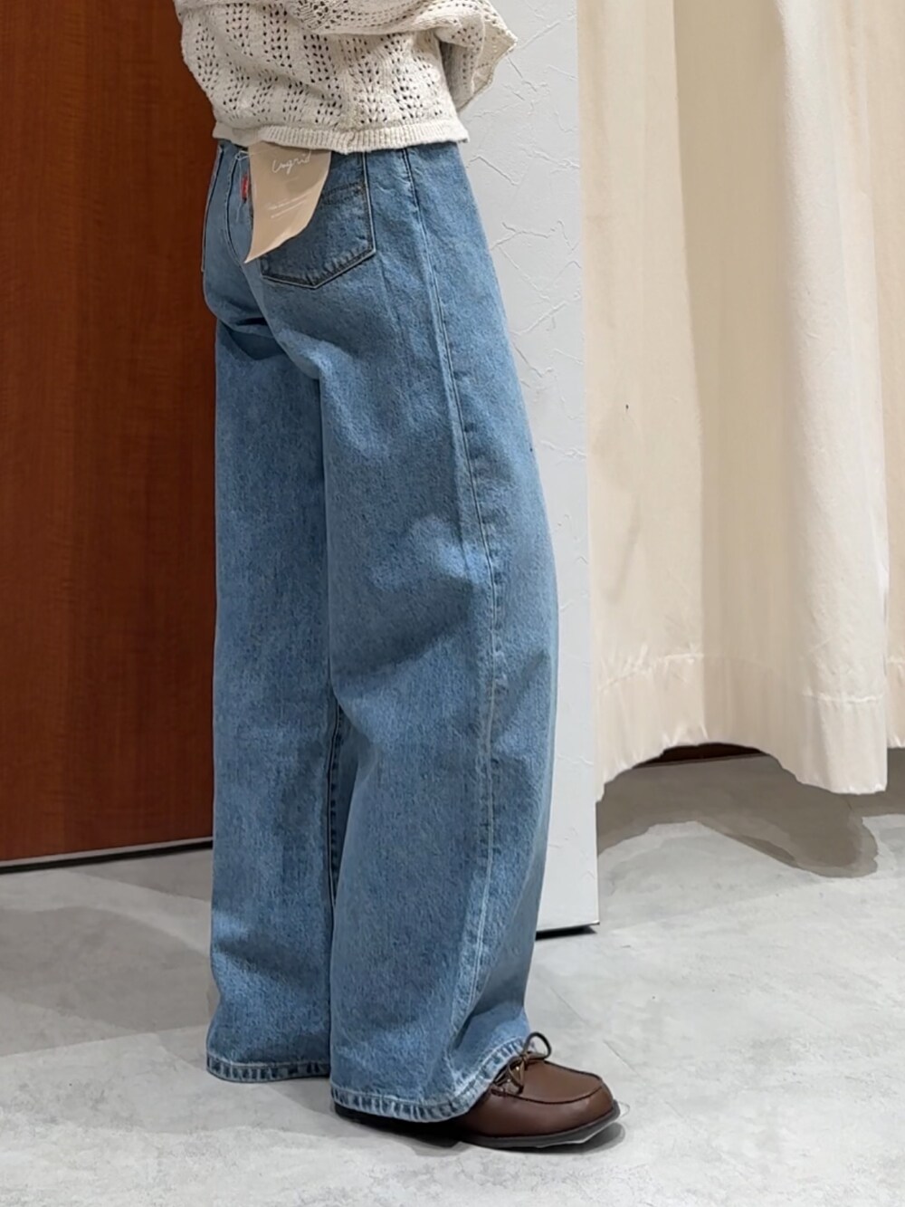 ブルー系のデニムパンツ、オレンジ系のタンクトップ、ホワイト系のカーディガン/ボレロを着用したレディースの春コーディネートの4枚目の写真