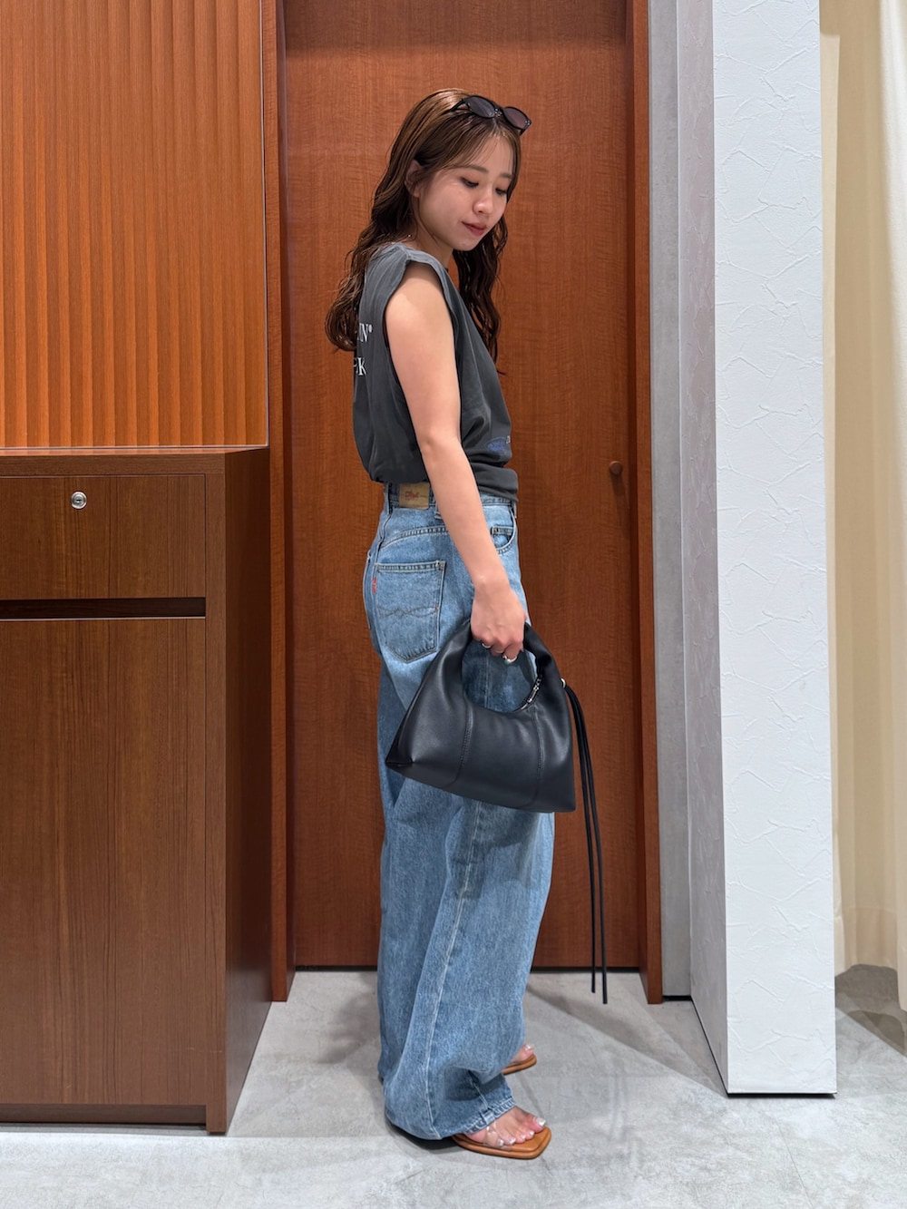 グレー系のタンクトップ、ブルー系のデニムパンツ、その他のサンダルを着用したレディースの夏コーディネートの3枚目の写真