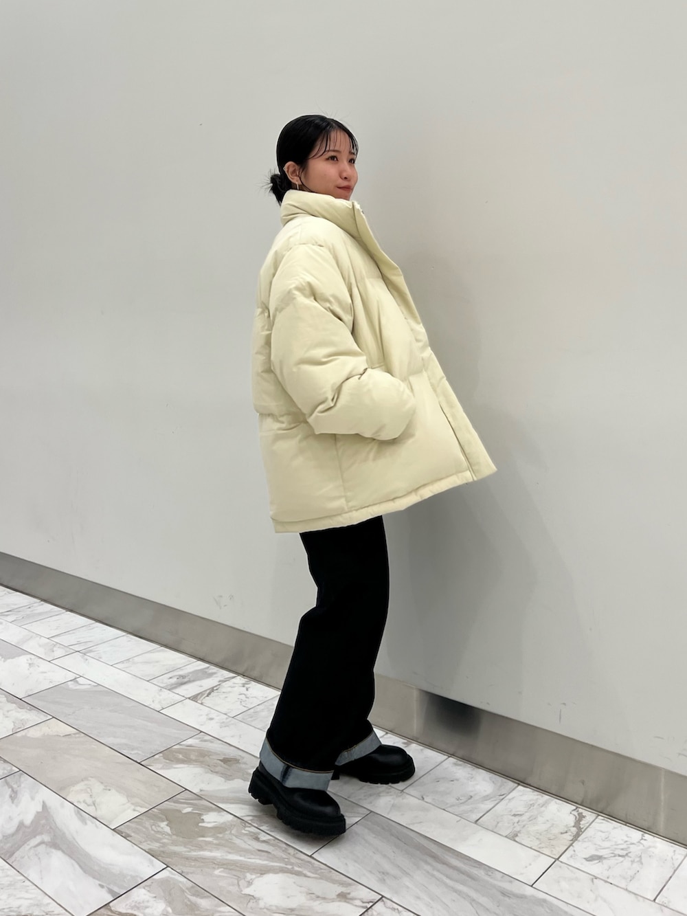 オレンジ系のニット/セーター、ブルー系のデニムパンツ、ホワイト系のダウンジャケット/コートを着用したレディースの秋コーディネートの4枚目の写真