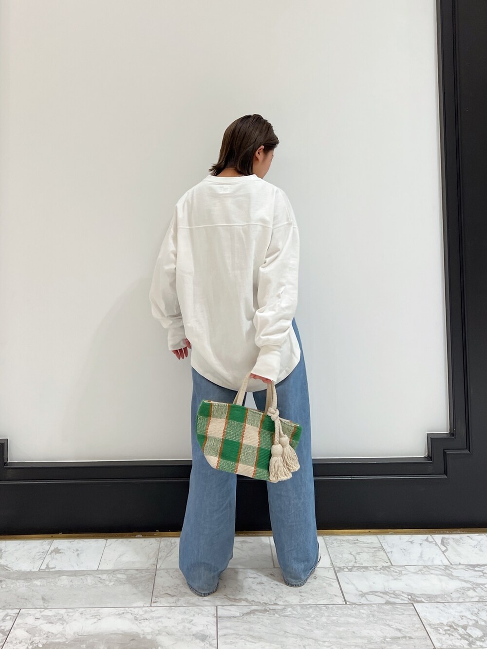 ブルー系のデニムパンツ、グリーン系のスニーカーを着用したレディースの春コーディネートの3枚目の写真