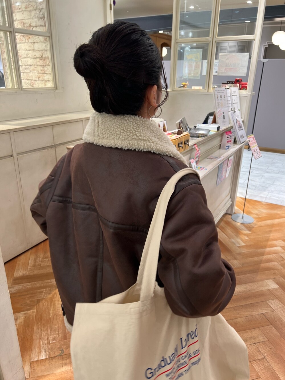 オレンジ系のニット/セーター、ホワイト系のTシャツ/カットソー、ブルー系のデニムパンツを着用したレディースの冬コーディネートの5枚目の写真