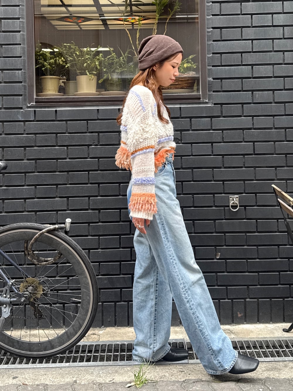 ブルー系のデニムパンツ、ホワイト系のニット/セーター、ブラック系のサンダルを着用したレディースの秋コーディネートの6枚目の写真