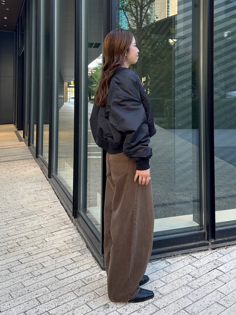 ブラウン系のデニムパンツ、ホワイト系のTシャツ/カットソー、ブラック系のMA-1を着用したレディースの秋コーディネートの3枚目の写真