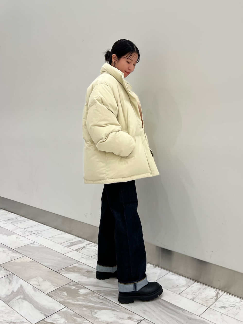 オレンジ系のニット/セーター、ブルー系のデニムパンツ、ホワイト系のダウンジャケット/コートを着用したレディースの秋コーディネートの3枚目の写真