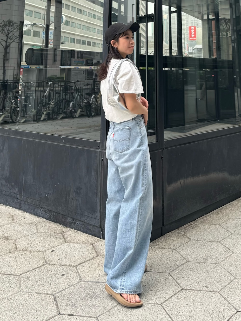 ブルー系のデニムパンツ、ホワイト系のTシャツ/カットソー、シルバー系のハンドバッグを着用したレディースの春コーディネートの4枚目の写真