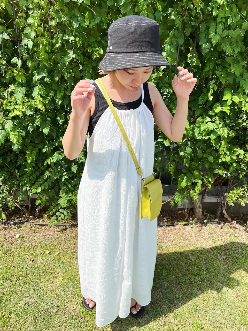 ブラック系のサンダル、ホワイト系のワンピース、ブラック系のタンクトップを着用したレディースの夏コーディネートの4枚目の写真