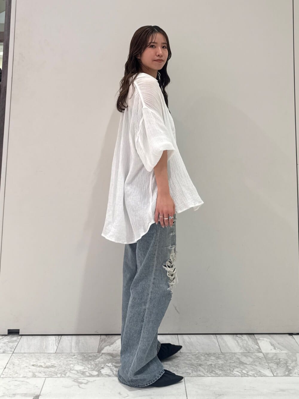 ブラック系のパンプス、ホワイト系のシャツ/ブラウス、ブルー系のデニムパンツを着用したレディースの春コーディネートの3枚目の写真