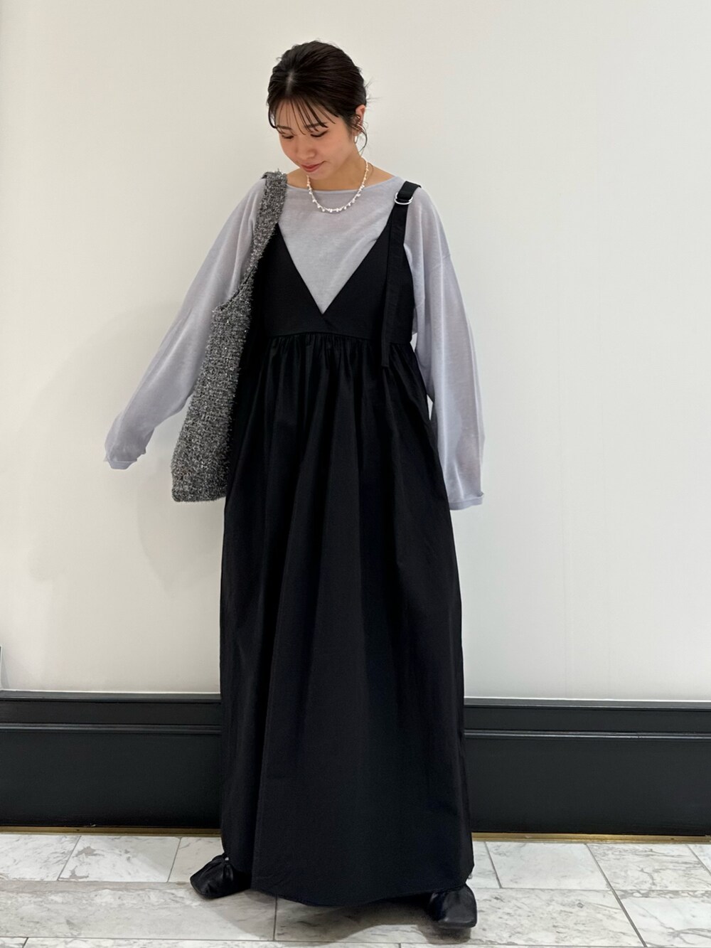 ブラック系のワンピース、ブルー系のニット/セーター、ブルー系のデニムパンツを着用したレディースの春コーディネートの4枚目の写真